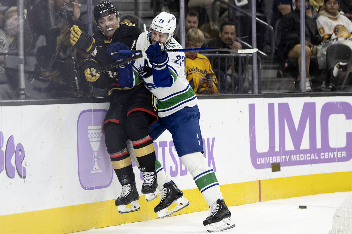 Canucks defenseman Oliver Ekman-Larsson (23) slams Golden Knights center Jake Leschyshyn (15) i ...