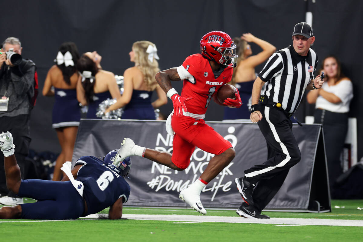 UNLV Rebels wide receiver Kyle Williams (1) dodges a tackle by Nevada Wolf Pack defensive back ...