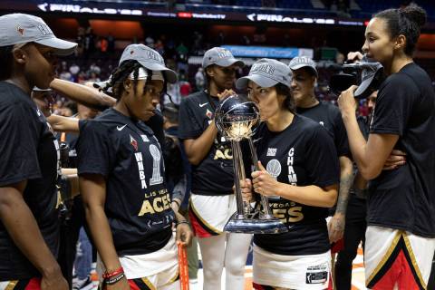 Las Vegas Aces guard Kelsey Plum (10) kisses the 2022 WNBA Championship trophy while teammates ...