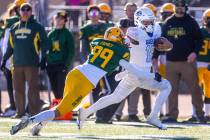 Bishop Gorman QB Micah Alejado (12) stiff arms Bishop Manogue DB Carson Jensen (99) to run down ...