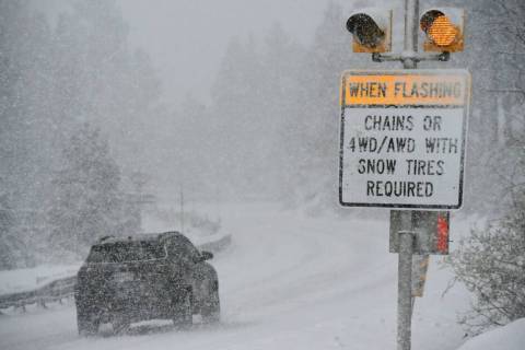 A car passes a caution sign as heavy snow falls on the Mt. Rose Highway near Reno, Nev., on Dec ...