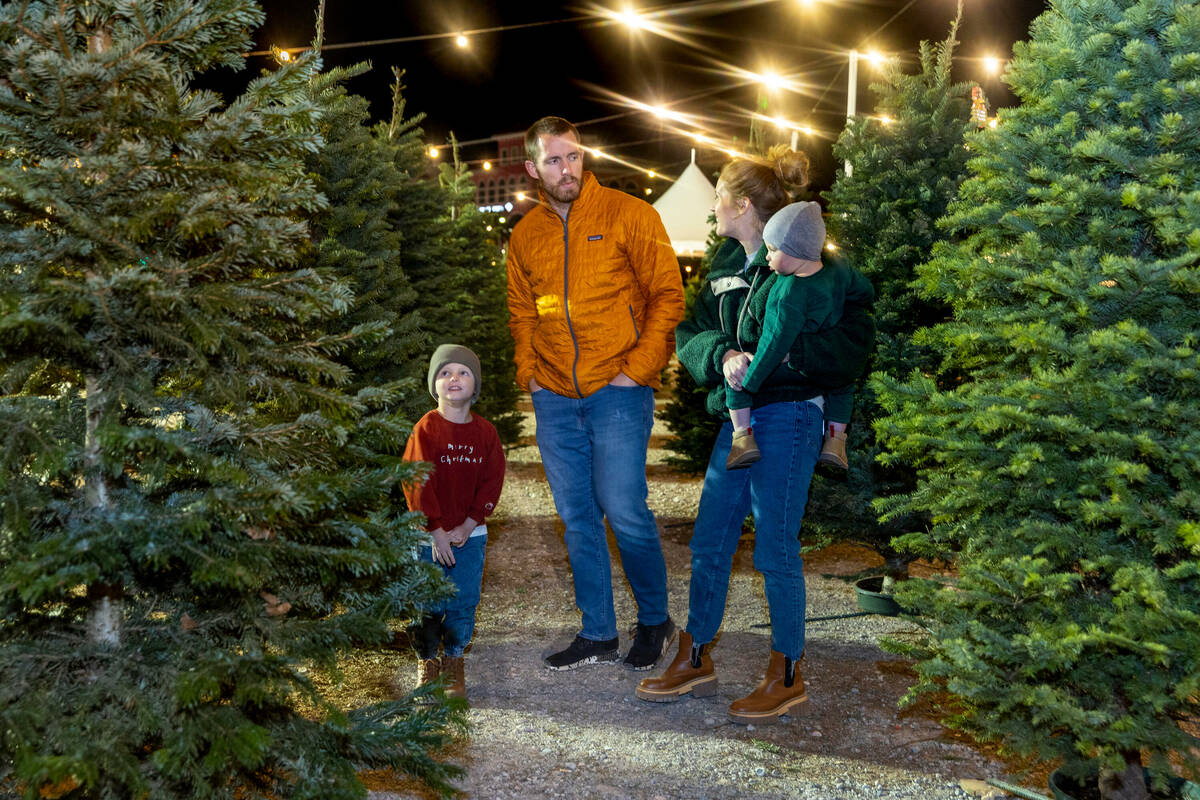 Calvin McDonough, 4, from left, looks to his tree selection as his father Travis confers with m ...