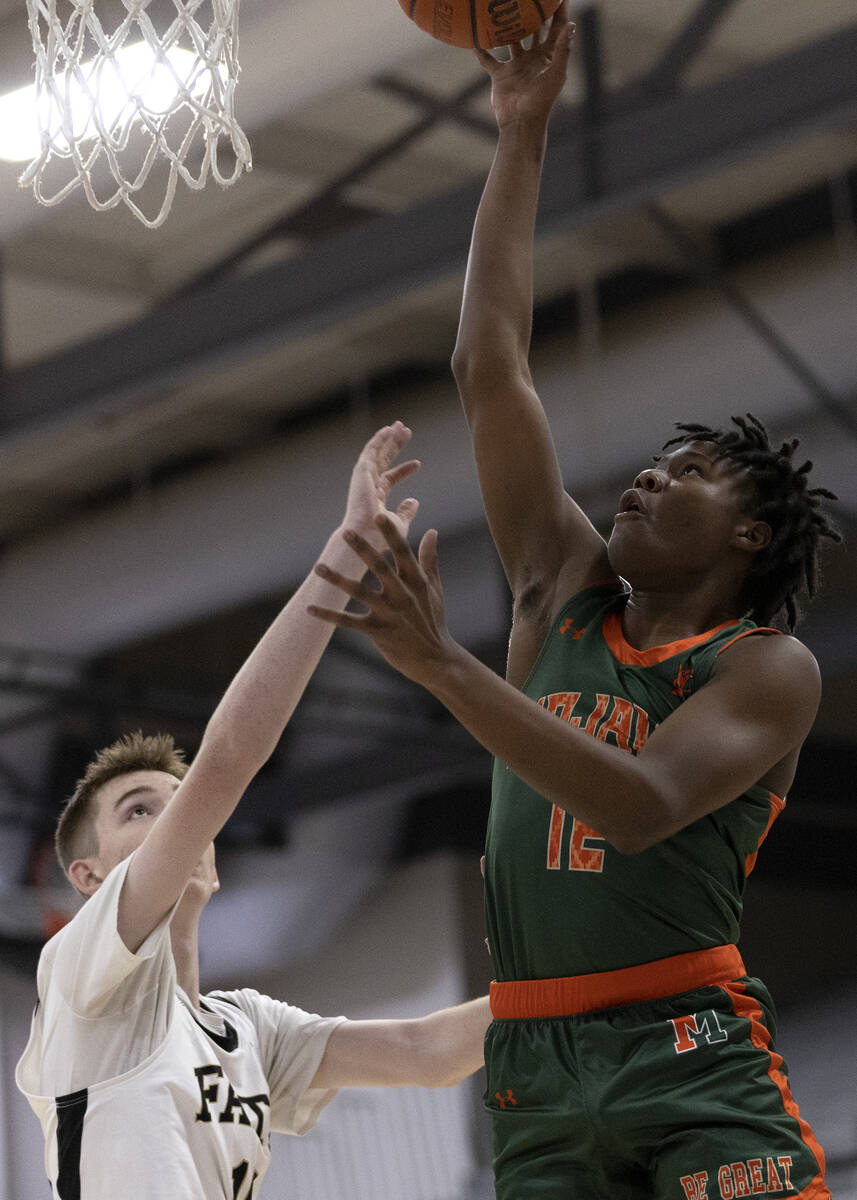 Mojave’s Montez Simmons (12) shoots against Faith Lutheran’s Graydon Lemke (15) d ...