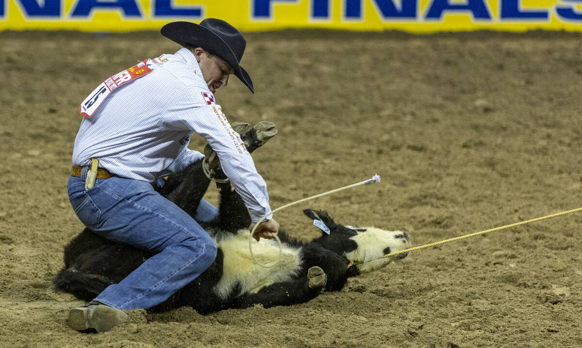 Caleb Smidt of Bellville, Texas, secures his calf while on a winning time in Tie-Down Roping du ...