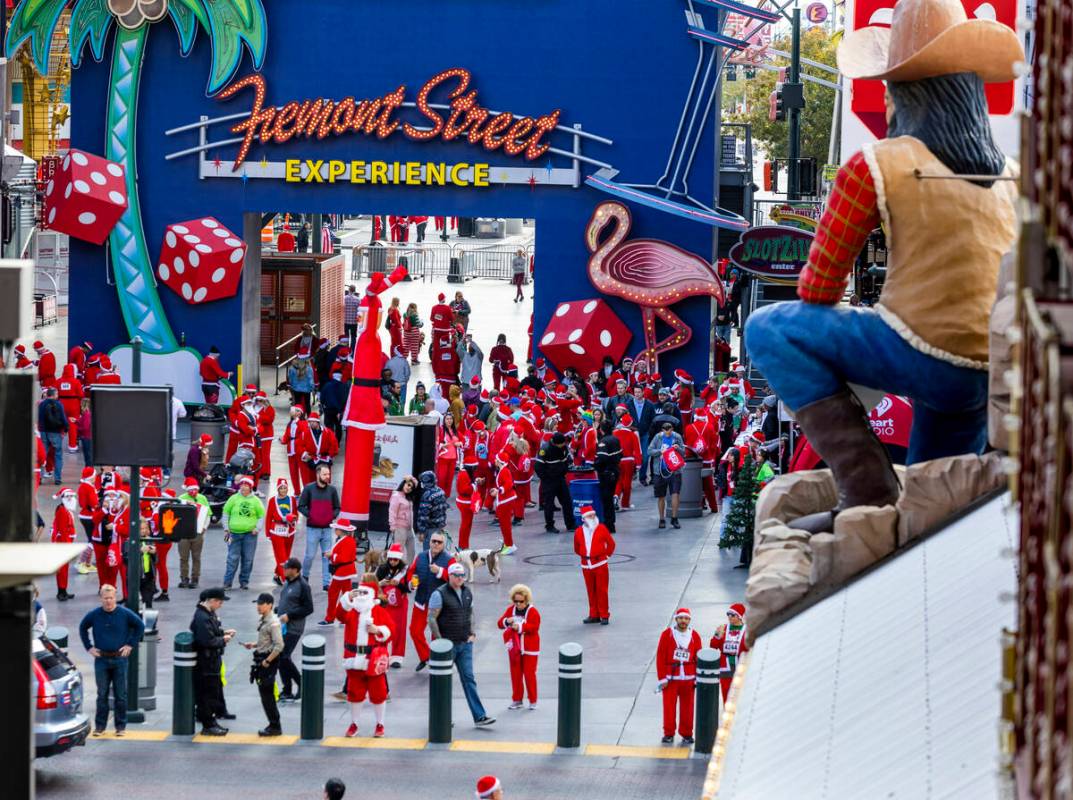 Participants clad in Santa outfits arrive for the pre-race entertainment at the Fremont Street ...