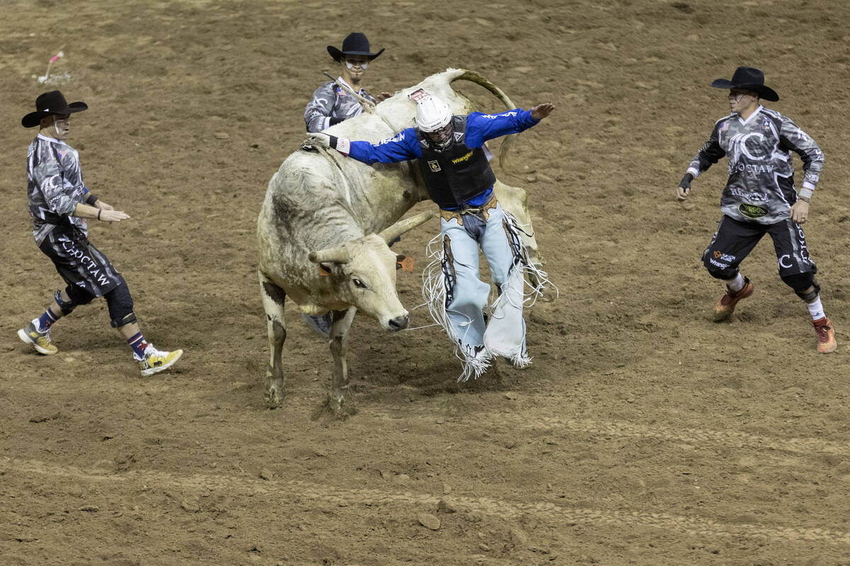 Arena crew close in on Creek Young, of Rogersville, Mo., as he is thrown from his animal while ...