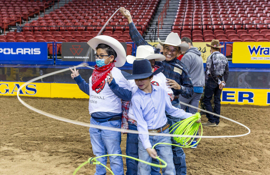 Participants Roman Chatfield, 8, left, and Jeremiah Brown, 8, center, have lassos twirled about ...