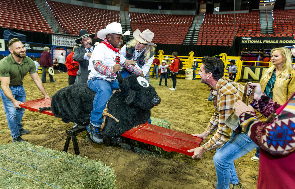 Participant Jeremiah Brown, 8, is assisted by Glee Nett as he rides a stuffed bull during the 3 ...