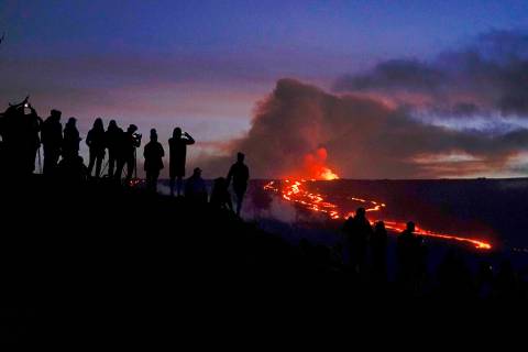 FILE - People watch and record images of lava from the Mauna Loa volcano Thursday, Dec. 1, 2022 ...