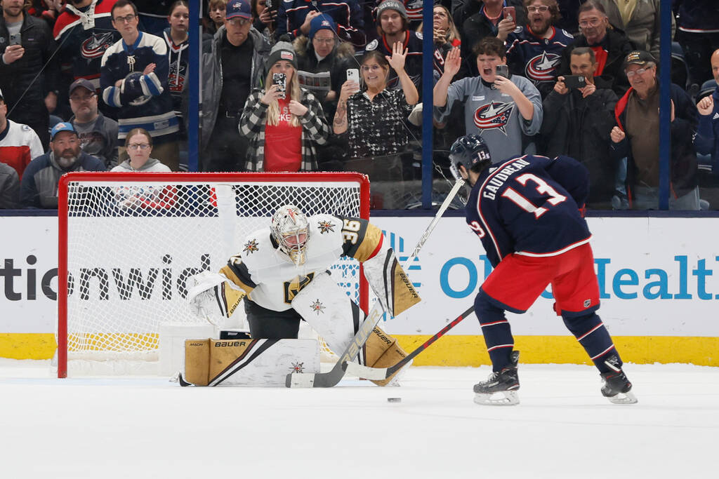 Vegas Golden Knights' Logan Thompson, left, makes a save against Columbus Blue Jackets' Johnny ...