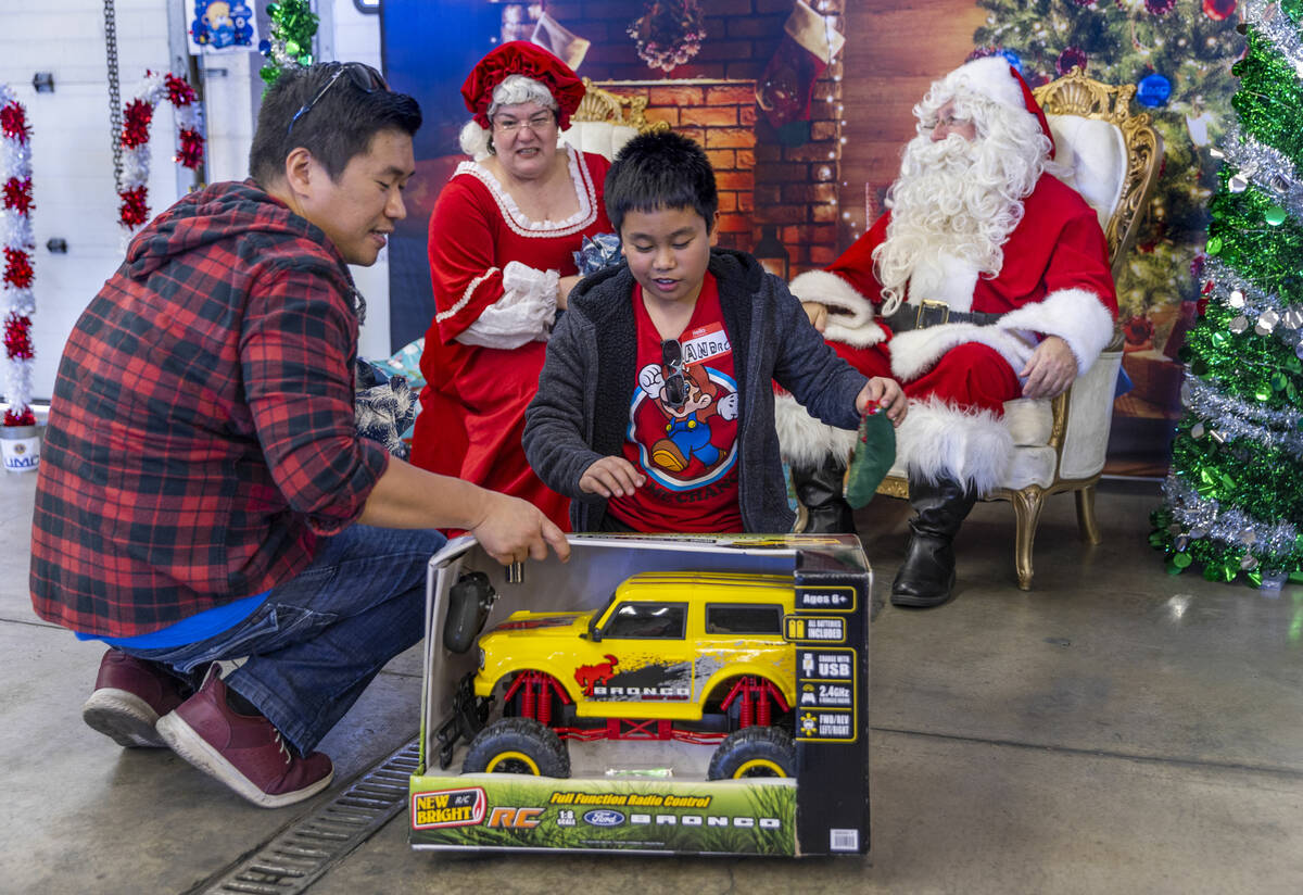 Blen Velonza, left, checks out a large toy truck given to his son Andre by Santa and Mrs. Claus ...