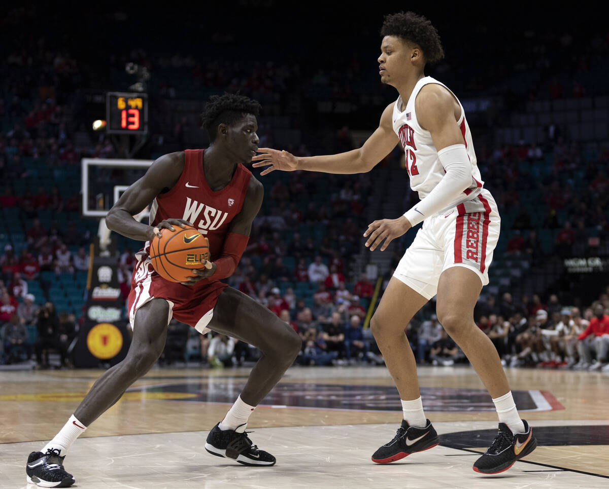 Washington State Cougars forward Mouhamed Gueye, left, dribbles against UNLV Rebels center Davi ...