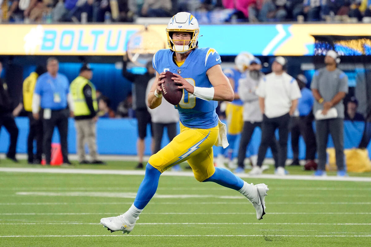 Los Angeles Chargers quarterback Justin Herbert rolls out during the first half of an NFL footb ...