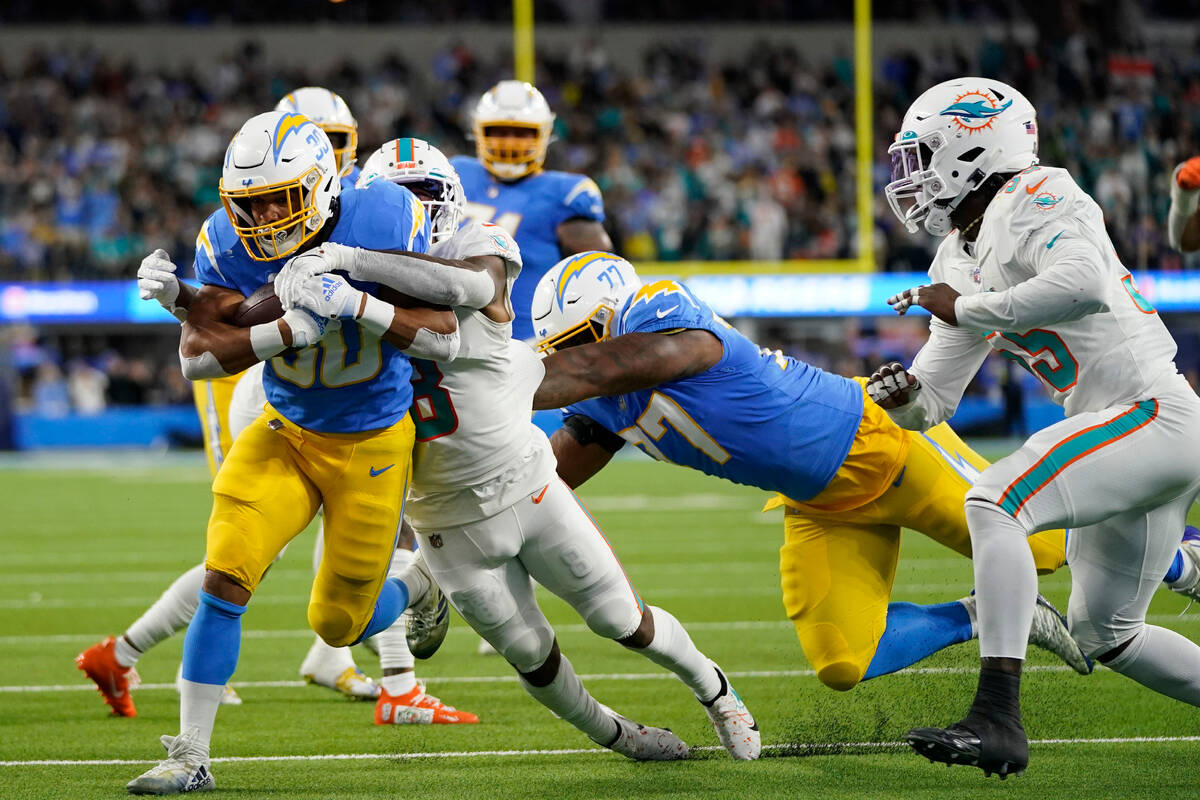 Los Angeles Chargers running back Austin Ekeler is tackled by Miami Dolphins safety Jevon Holla ...