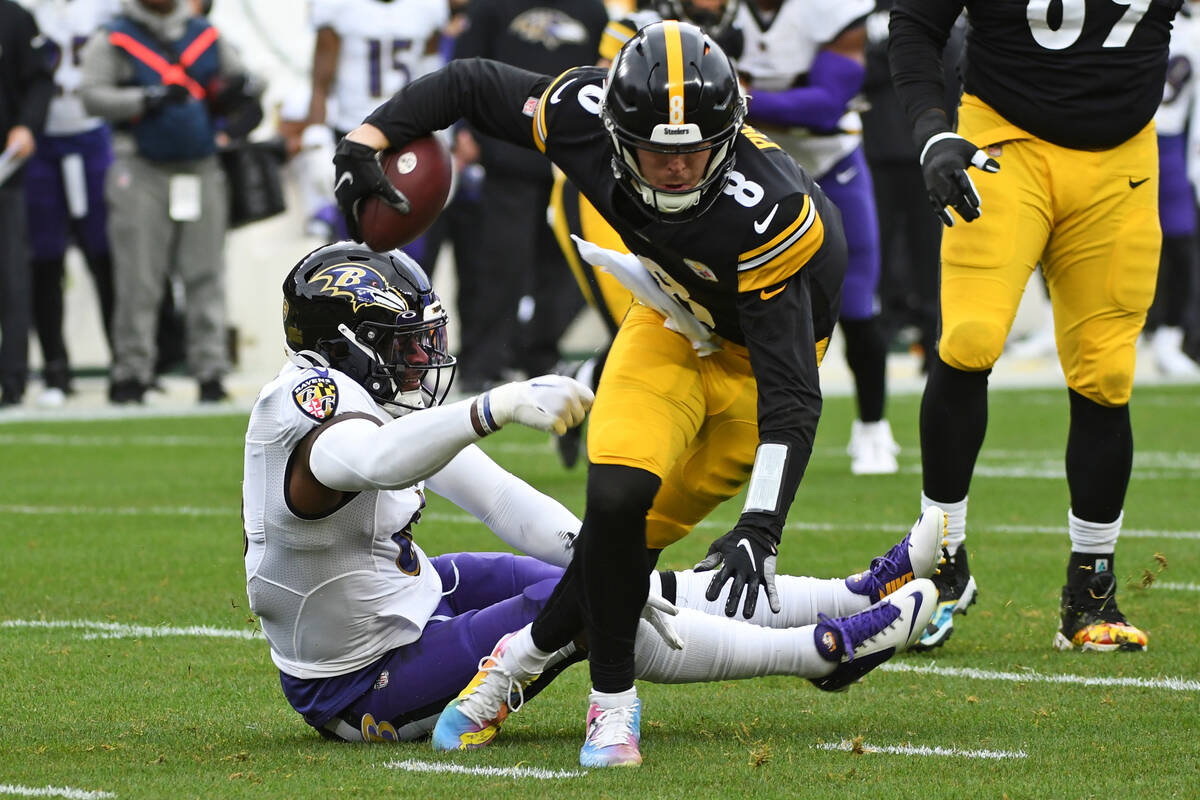 Pittsburgh Steelers quarterback Kenny Pickett (8) slips out of the grasp of Baltimore Ravens li ...