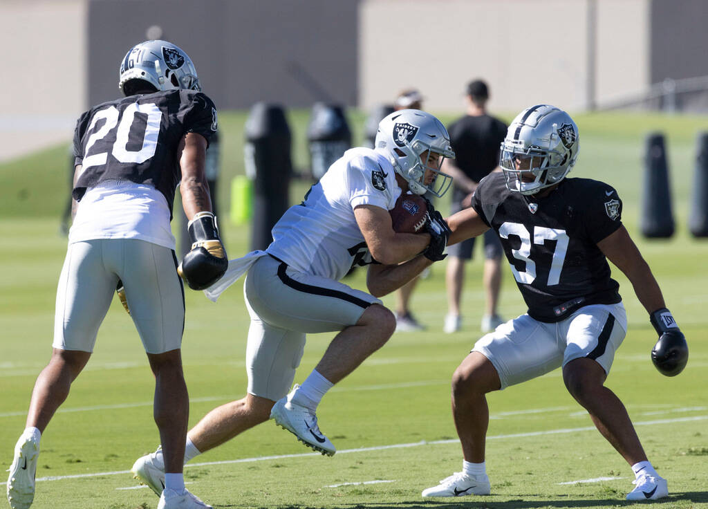Raiders wide receiver Hunter Renfrow (13) holds on to the football as safety Isaiah Pola-Mao (2 ...