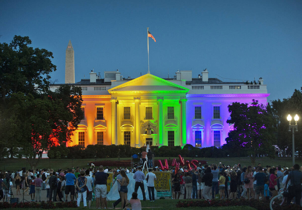 FILE - People gather in Washington's Lafayette Park to see the White House illuminated with rai ...