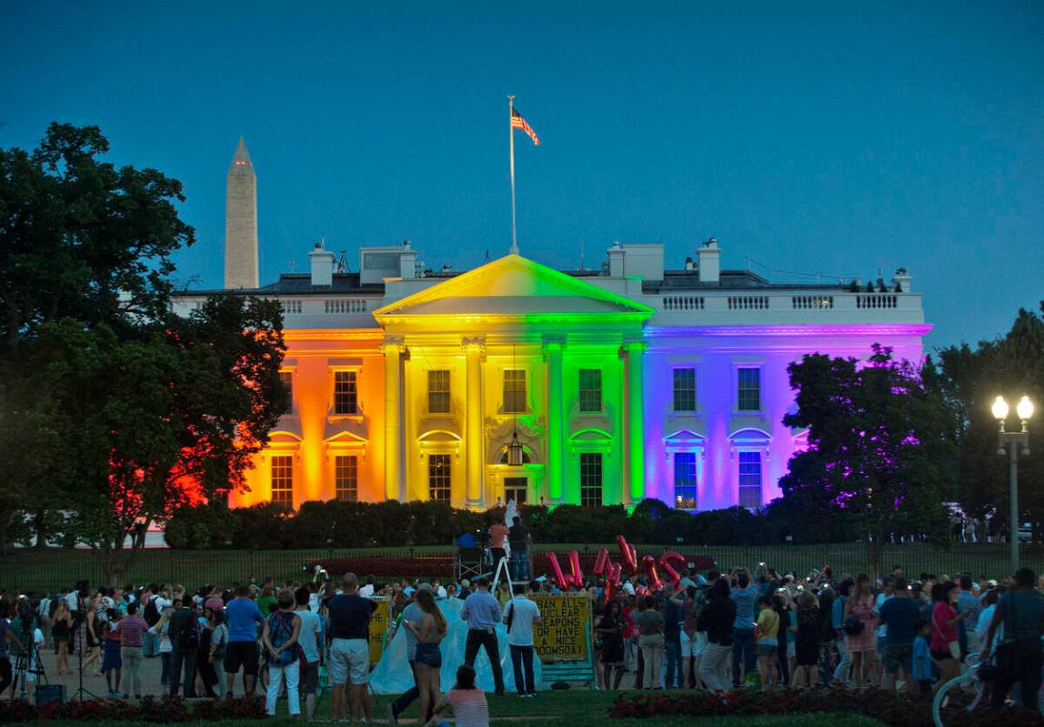 FILE - People gather in Washington's Lafayette Park to see the White House illuminated with rai ...