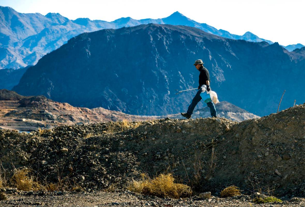 Volunteer Kevin Long of Henderson with Get Outdoors Nevada eyes a rock berm for trash as his or ...