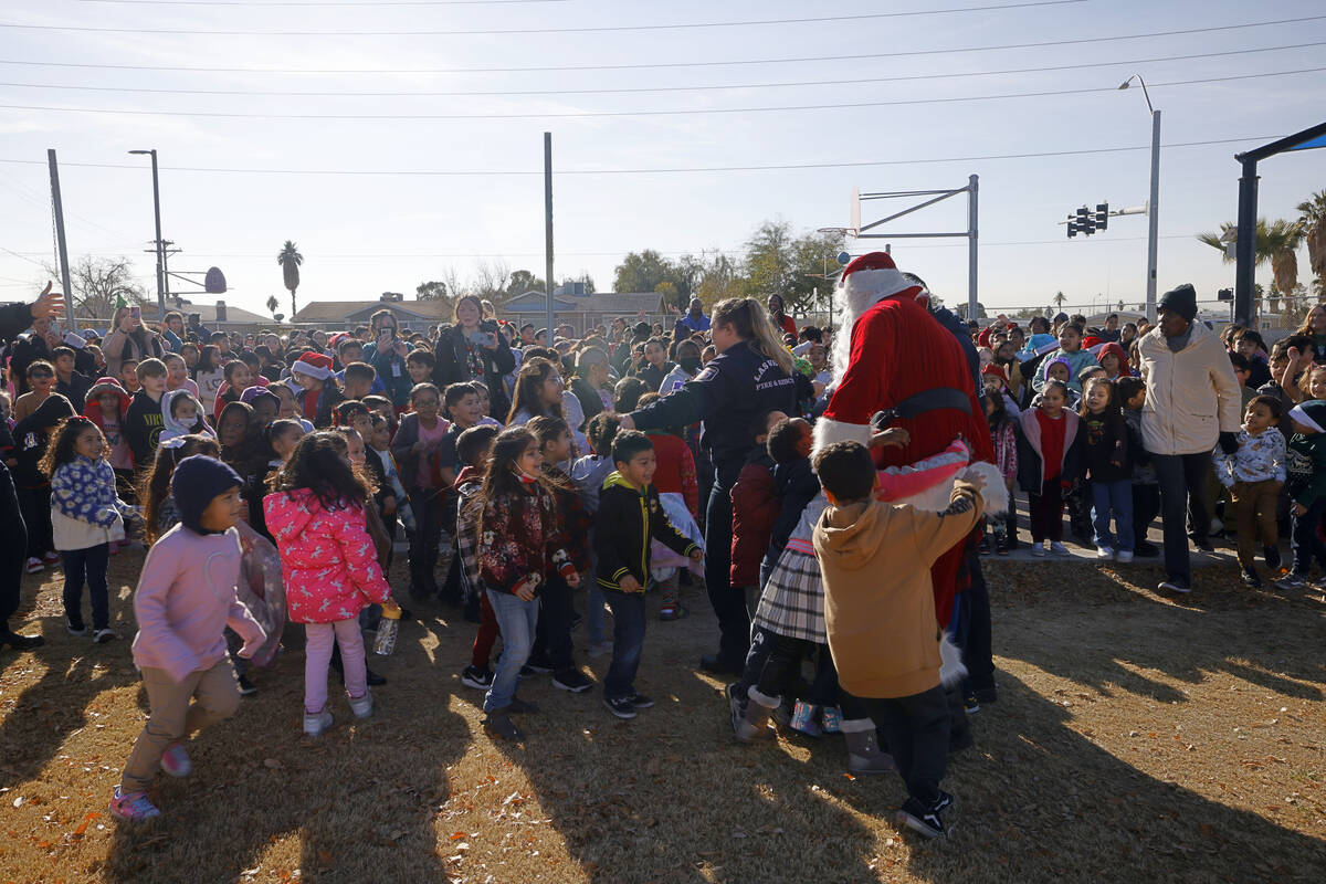 Santa Claus greets the students after he arrived at Fay Herron Elementary School by helicopter, ...