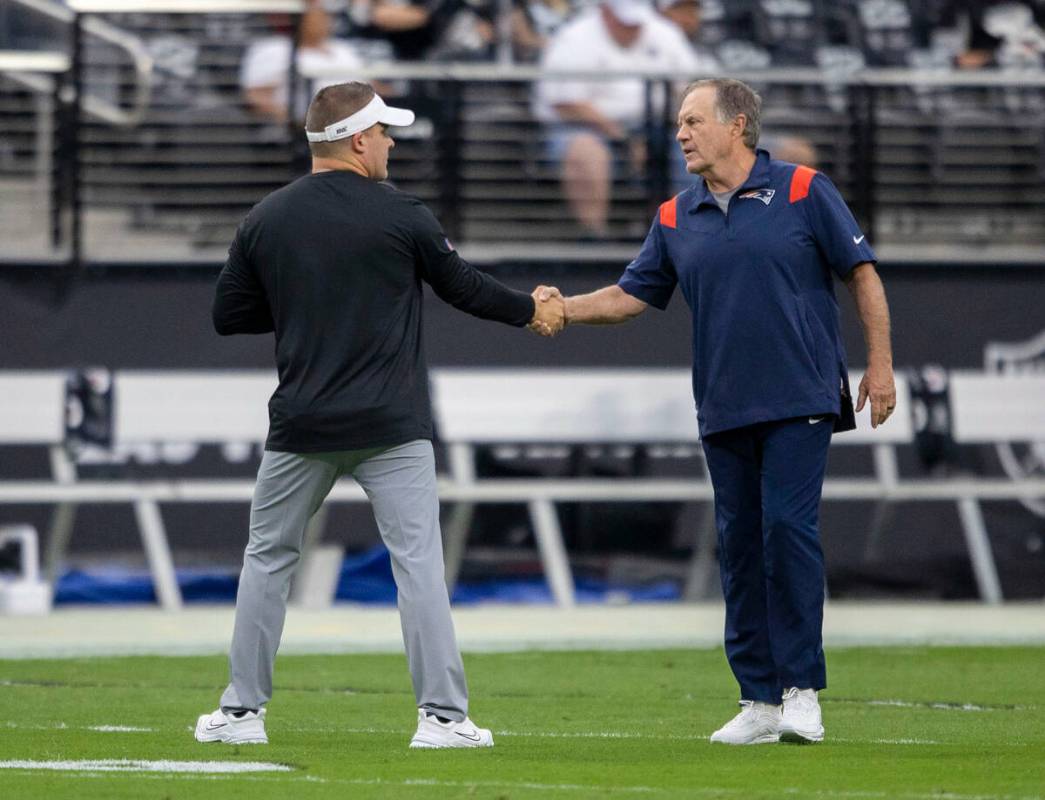 Raiders head coach Josh McDaniels, left, and New England Patriots head coach Bill Belichick sha ...