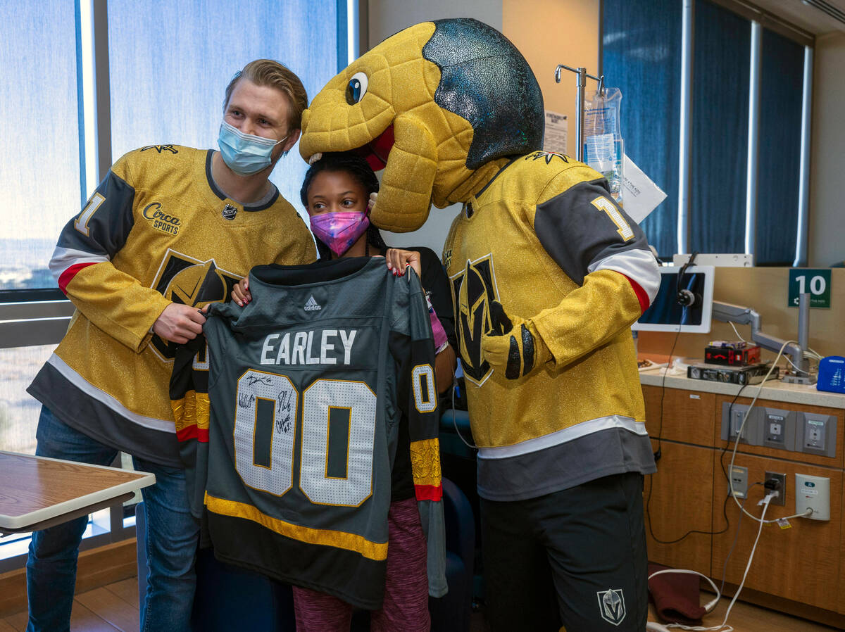 William Karlsson (81) joins patient Mykala Earley and mascot Chance the Gila monster for a phot ...