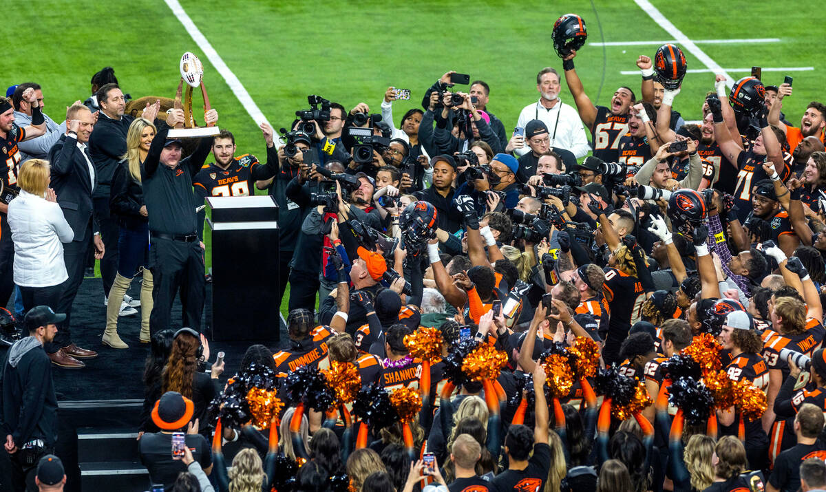 Oregon State Beavers Head Coach Jonathan Smith holds up the Rossi Ralenkotter trophy after his ...