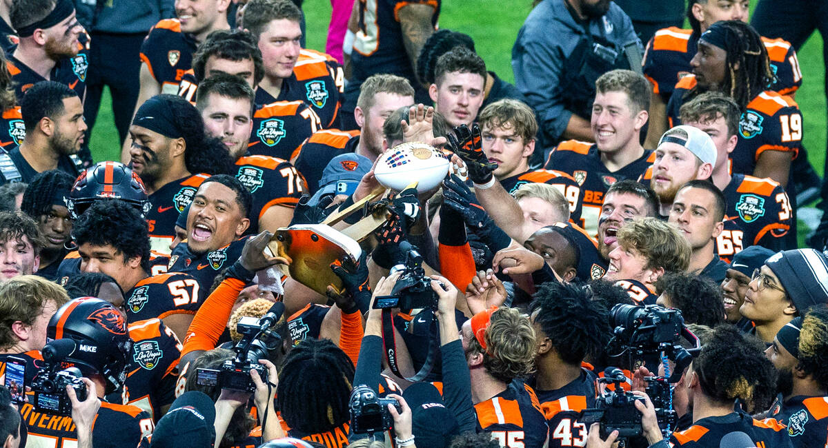 Oregon State Beavers players touch and pass along the Rossi Ralenkotter trophy after defeating ...