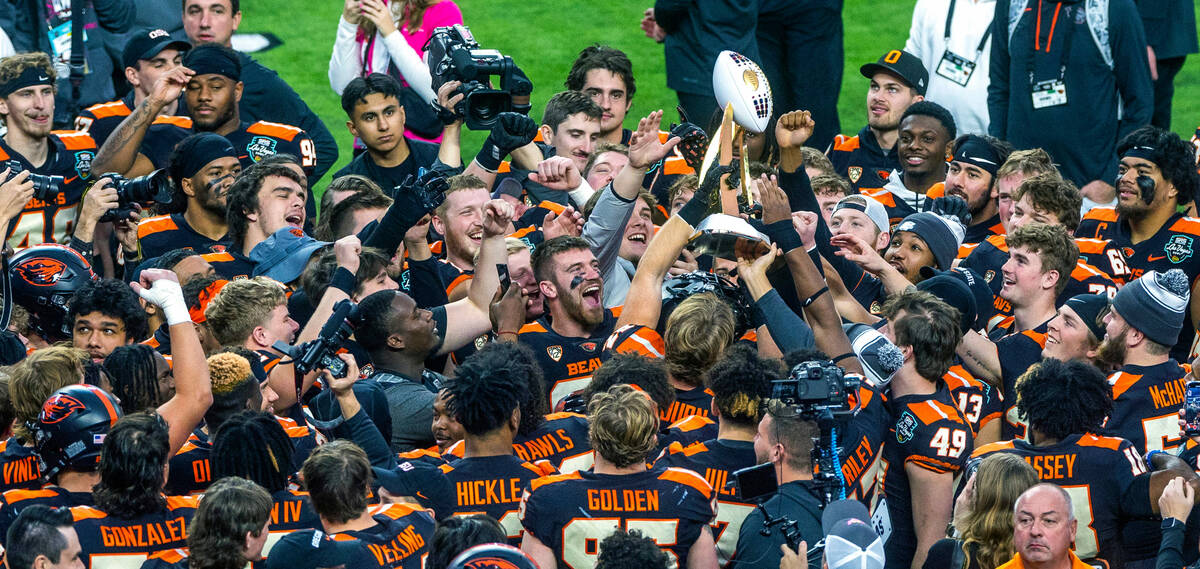 Oregon State Beavers players touch and pass along the Rossi Ralenkotter trophy after defeating ...