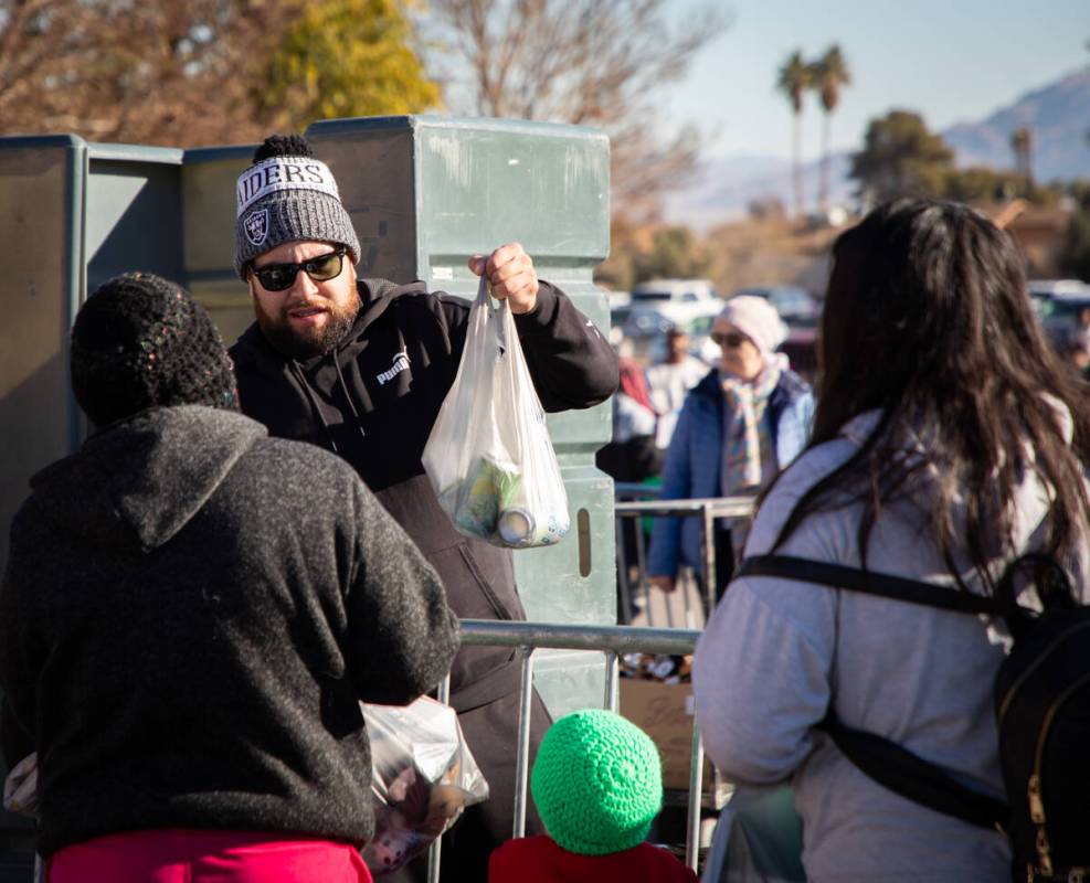 Gabriel Diaz, volunteer, passes out a bag of groceries to people during the Las Vegas Rescue Mi ...