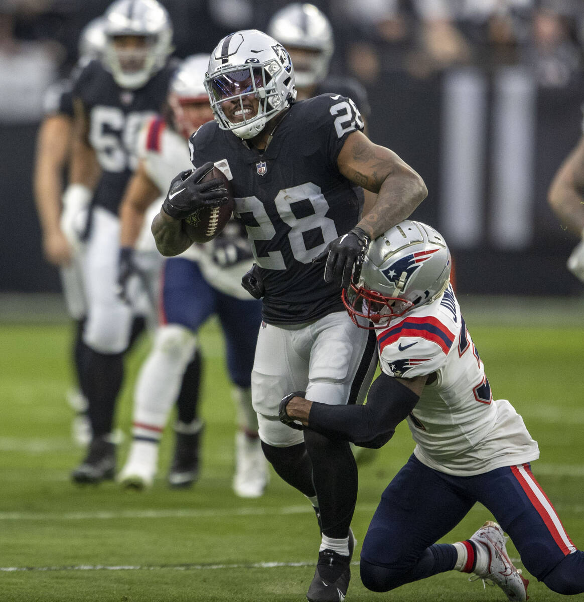 Raiders running back Josh Jacobs (28) is tackled by New England Patriots cornerback Jonathan Jo ...