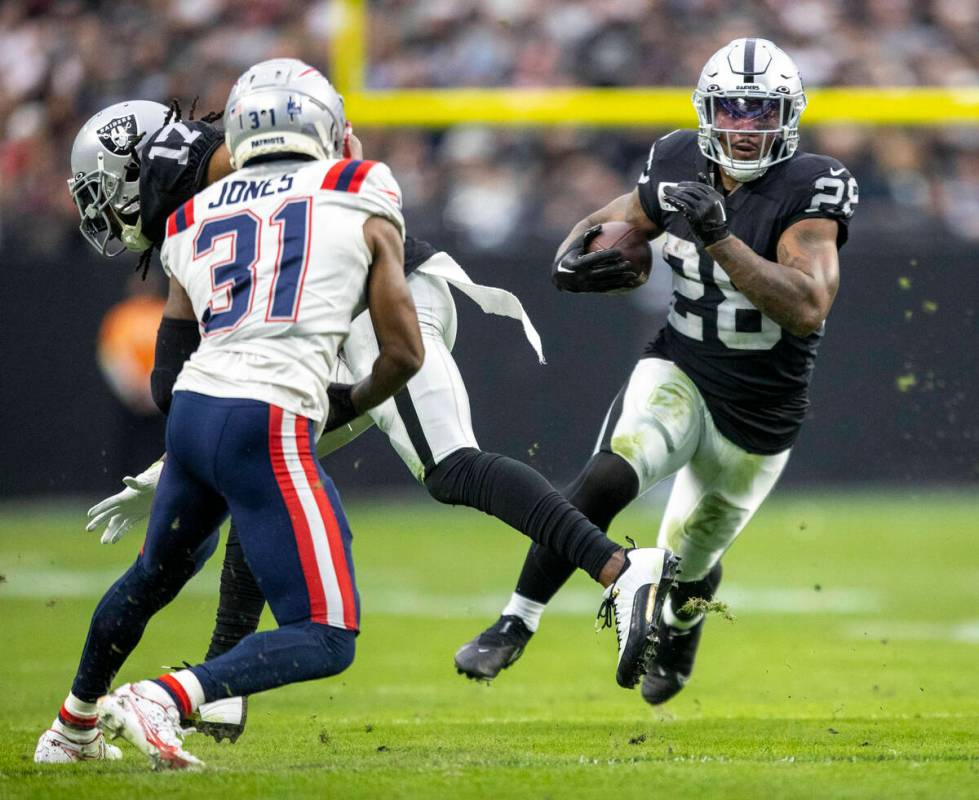 Raiders running back Josh Jacobs (28) runs against New England Patriots cornerback Jonathan Jon ...