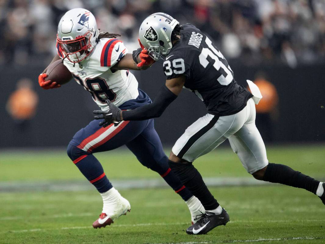 New England Patriots running back Rhamondre Stevenson (38) stiff arms Raiders cornerback Nate H ...