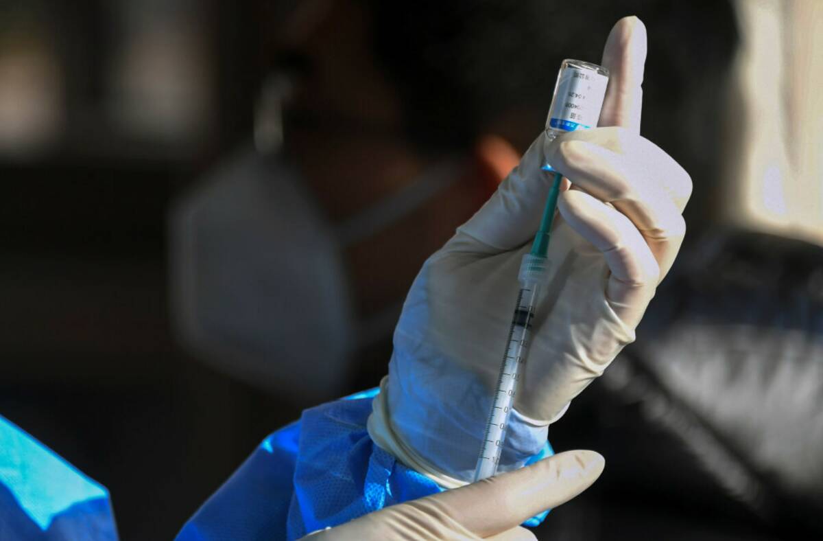 A medical worker prepares to administer a second booster dose of COVID-19 vaccine for a residen ...