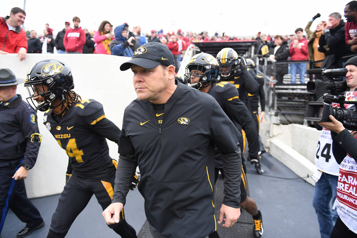 Missouri head coach Barry Odom leads his team onto the field to play Arkansas during an NCAA co ...