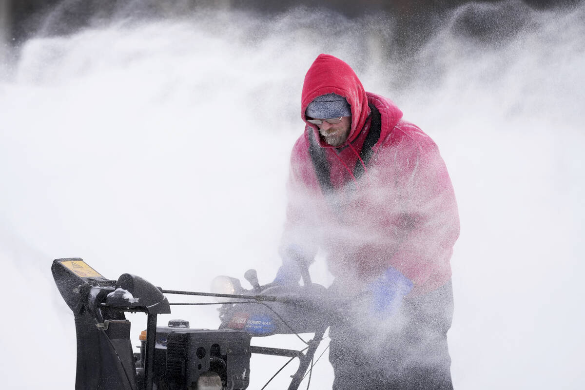 Mark Sorter clears snow from a downtown ice skating rink, Friday, Dec. 23, 2022, in Des Moines, ...