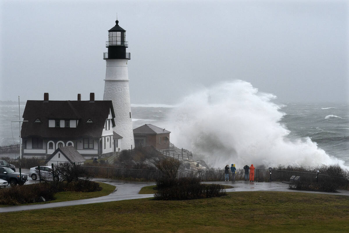 A wave slams into the rocks at Portland Head Light, Maine, during a powerful winter storm, Frid ...