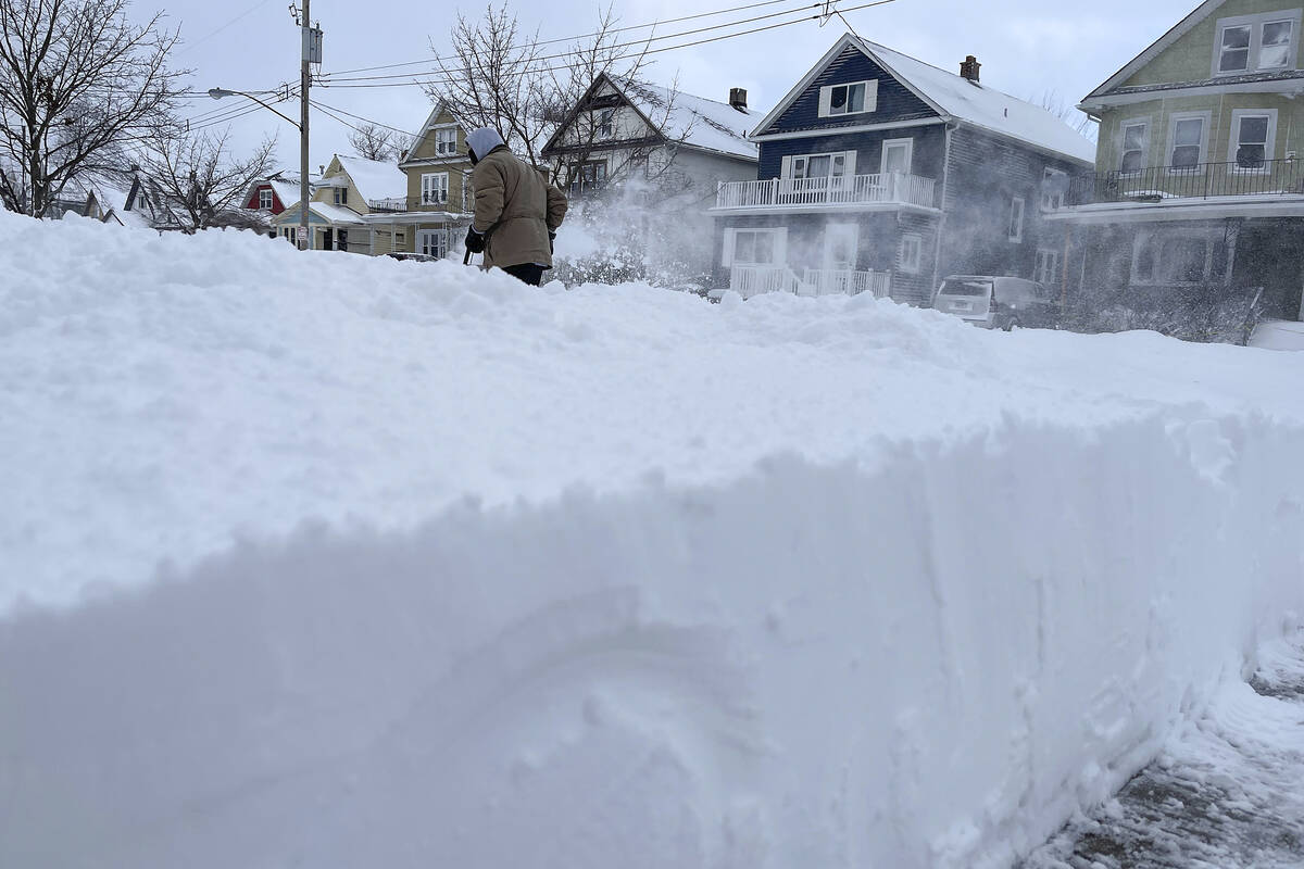 Martin Haslinger clears snow from the front of his home, Sunday, Dec. 25, 2022, in Buffalo, N.Y ...