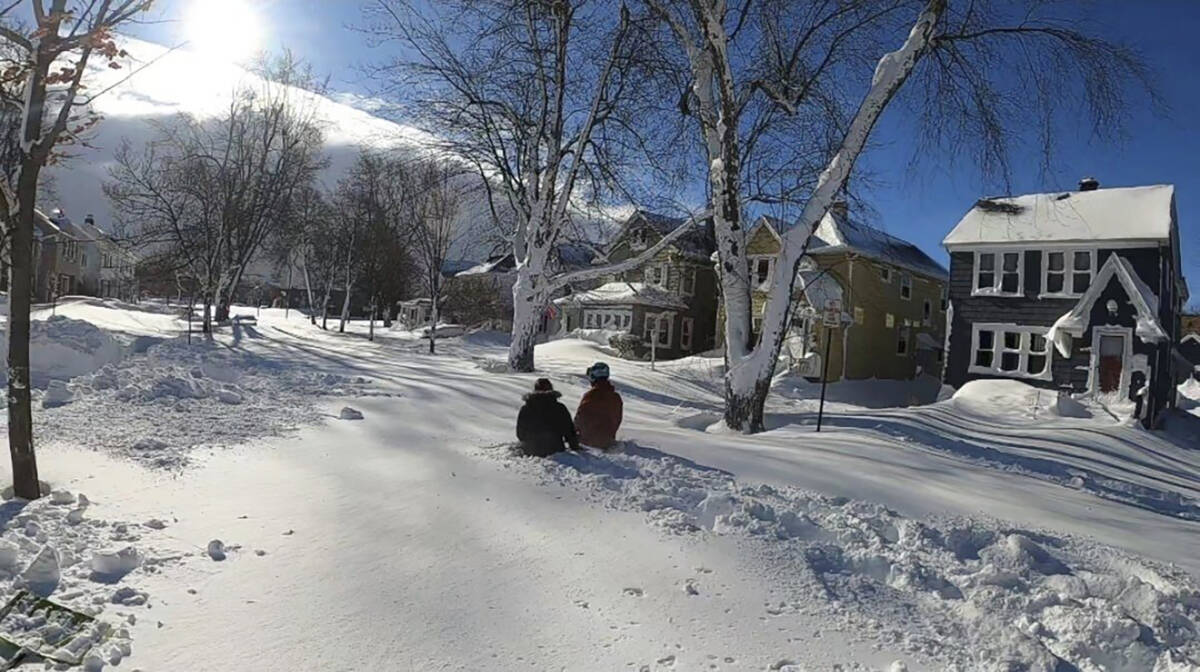 This photo provided by Clare Purcell shows two people sitting outside on their front lawn after ...