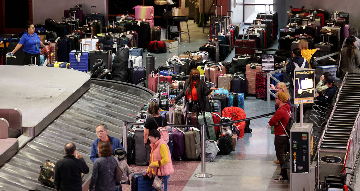 Travelers try to retrieve their luggage from cancelled and delayed flights in baggage claim of ...