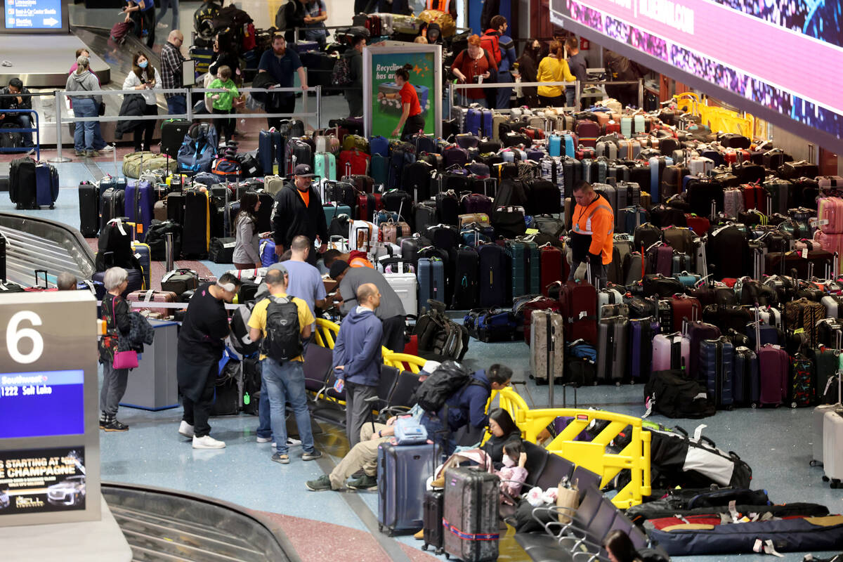 Travelers try to retrieve their luggage from cancelled and delayed flights in baggage claim of ...