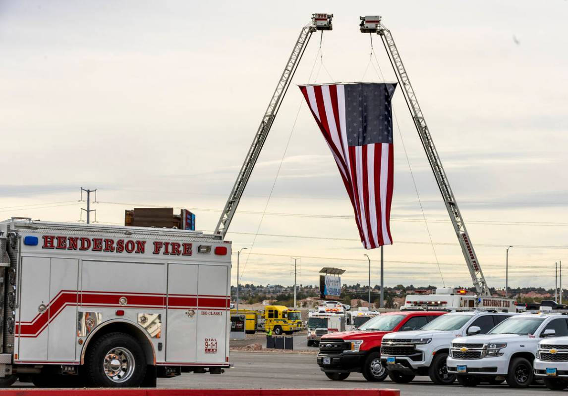 Emergency vehicles enter beneath a large American flag as Henderson Fire Department Engineer Cl ...