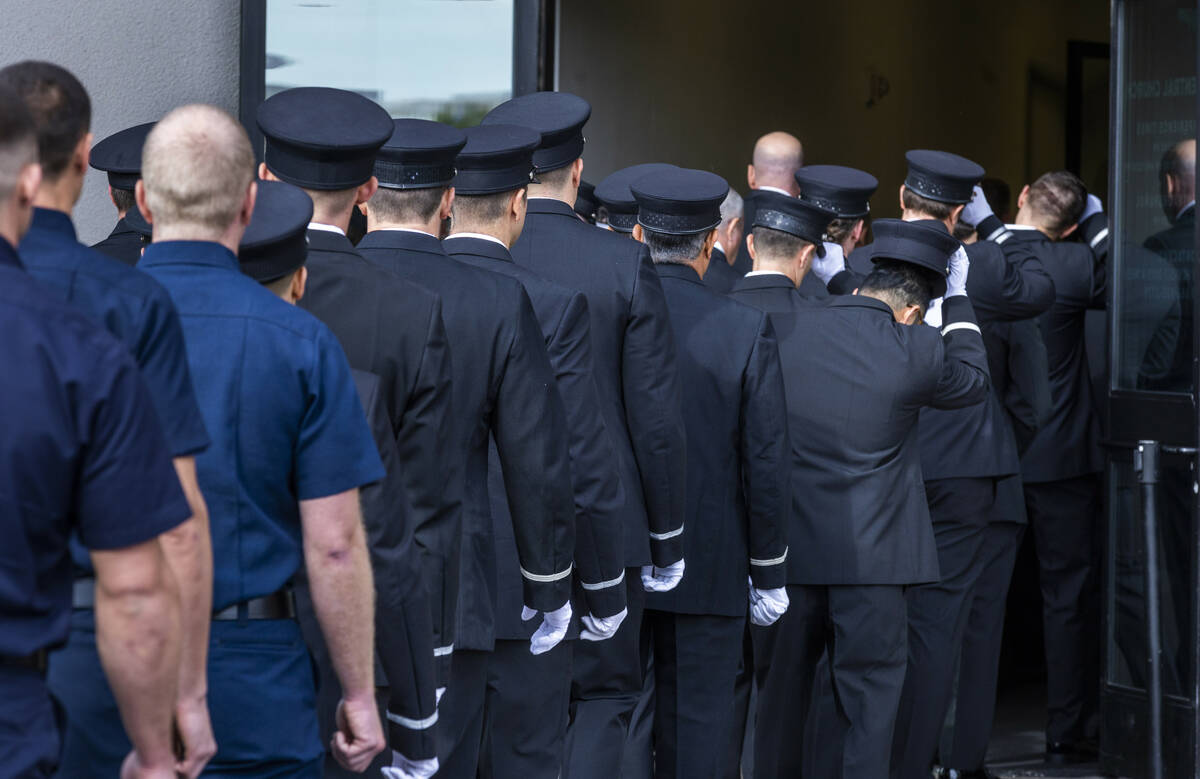 Mourners including coworkers and friends remove their hats while walking inside in the processi ...