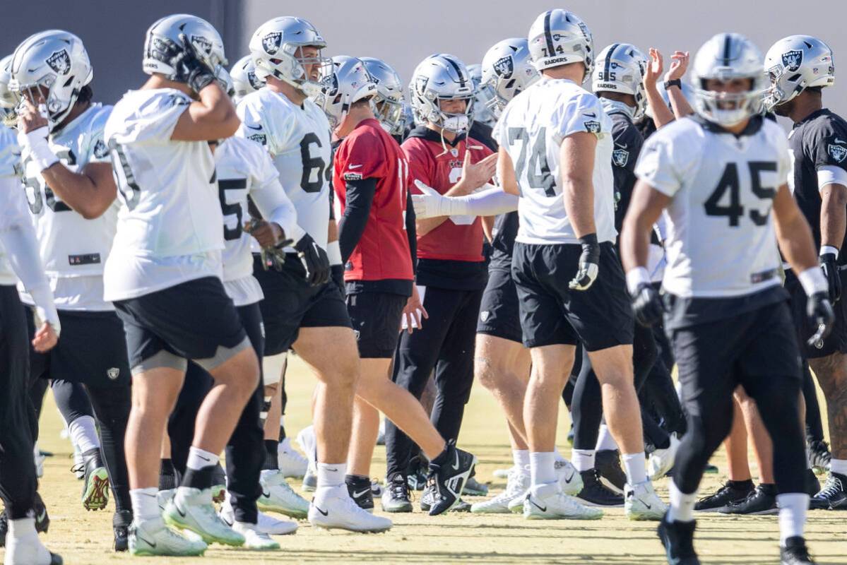 Raiders quarterback Jarrett Stidham (3), center, shakes hands with defensive end Maxx Crosby (9 ...