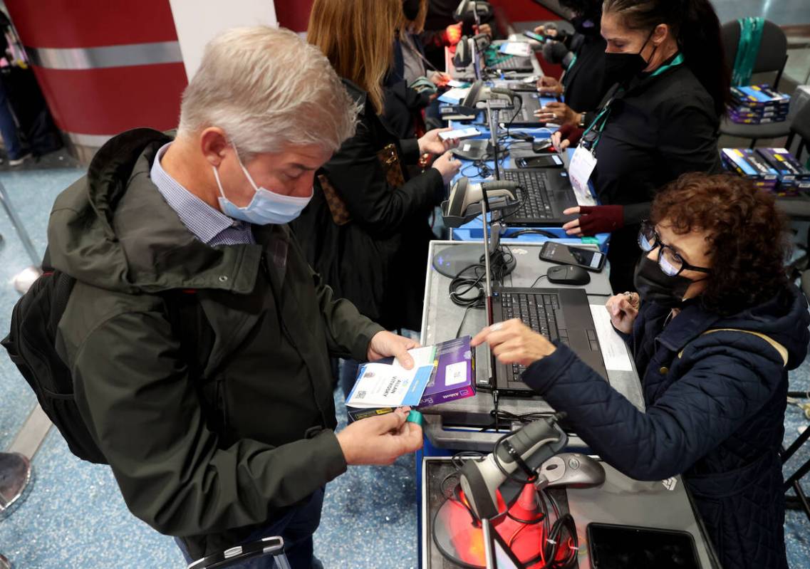 Allan Vitkosky of San Diego picks up his CES badge and COVID-19 test kit from Barbara Cuomo aft ...