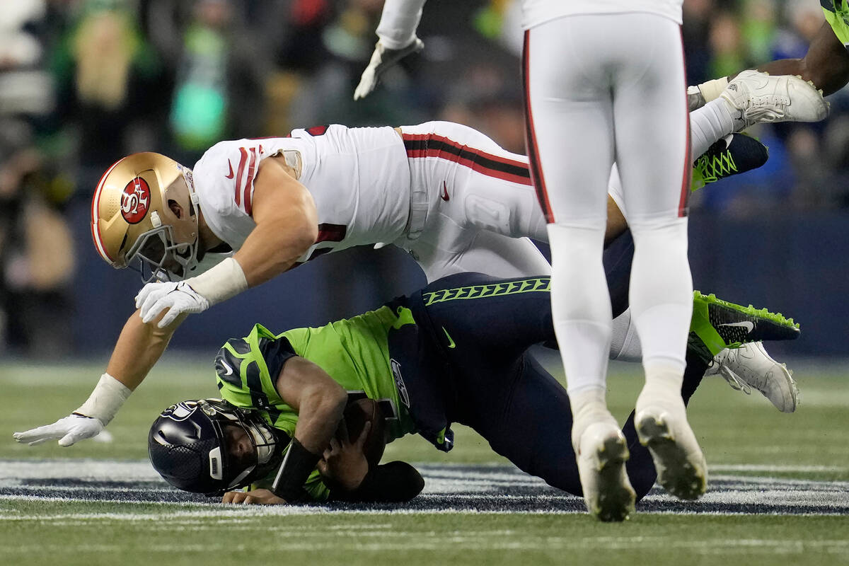 San Francisco 49ers defensive end Nick Bosa, top, sacks Seattle Seahawks quarterback Geno Smith ...