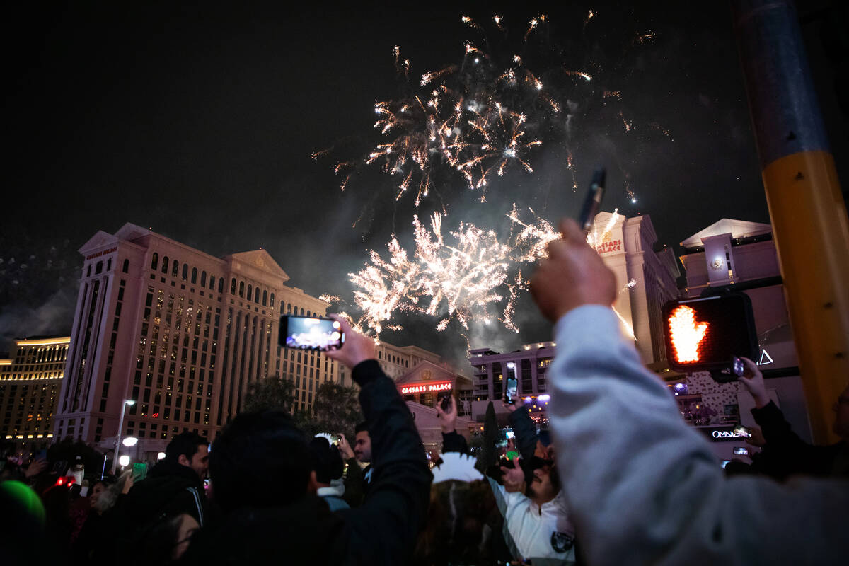 New Year’s revelers take photos and watch the fireworks on the Strip on Sunday, Jan. 1, 2023, ...