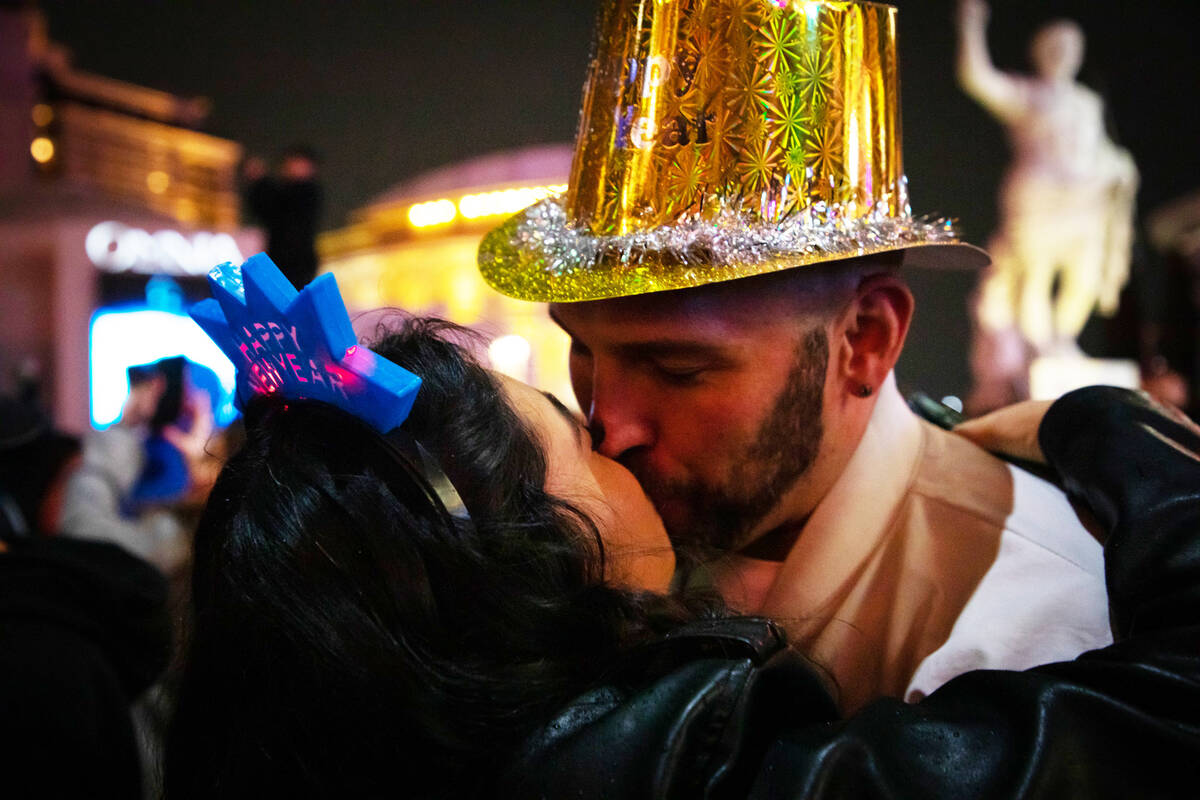 New Year’s revelers Wendy Flores, left, and Eric Oeser, right, share a New Year’s kiss duri ...