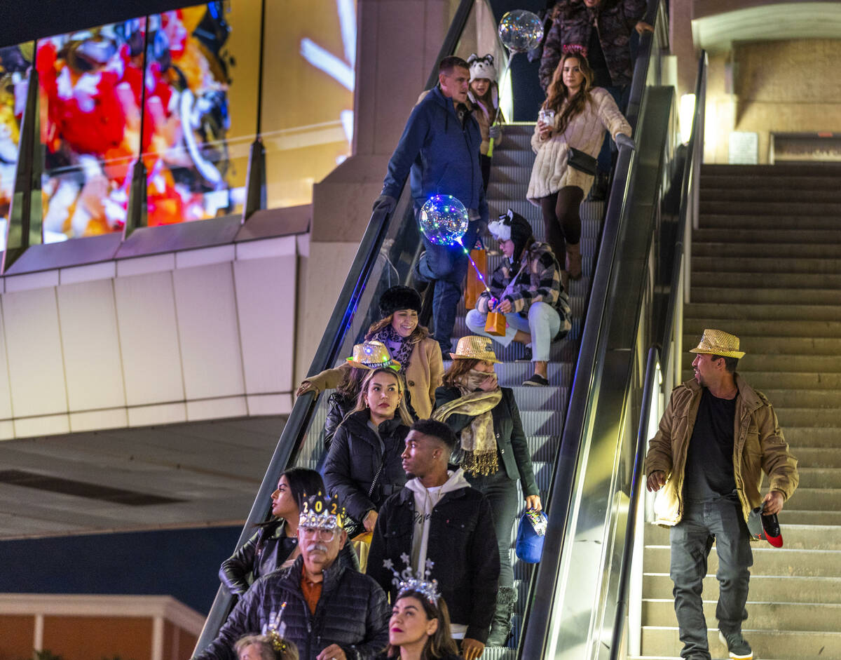 New Year’s Eve revelers move down an escalator near the Fashion Show mall along the Strip on ...