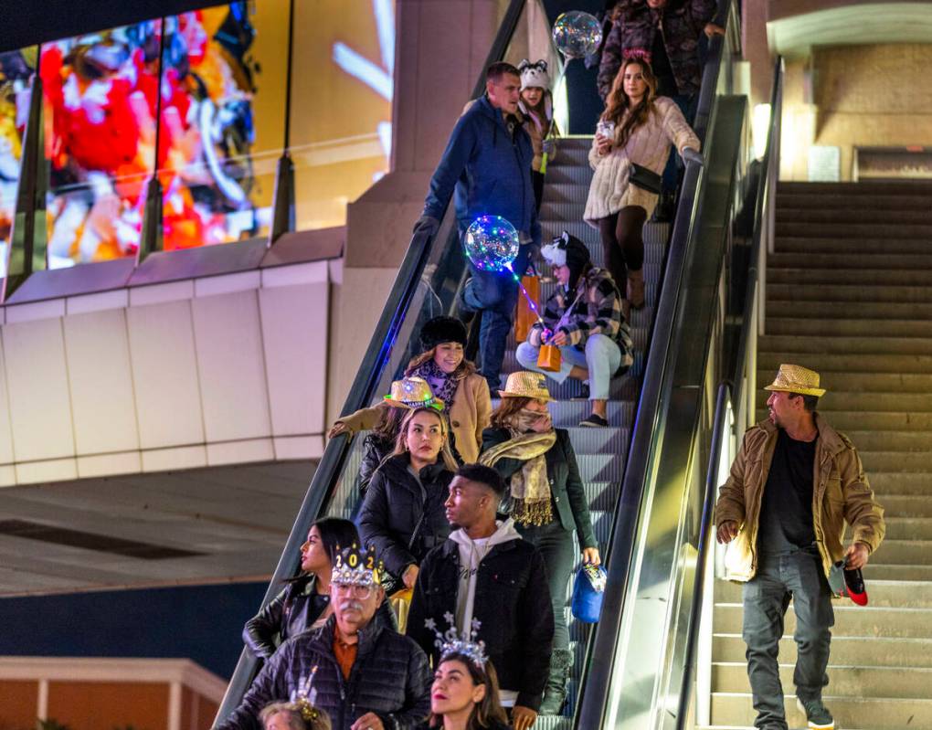 New Year’s Eve revelers move down an escalator near the Fashion Show mall along the Strip on ...